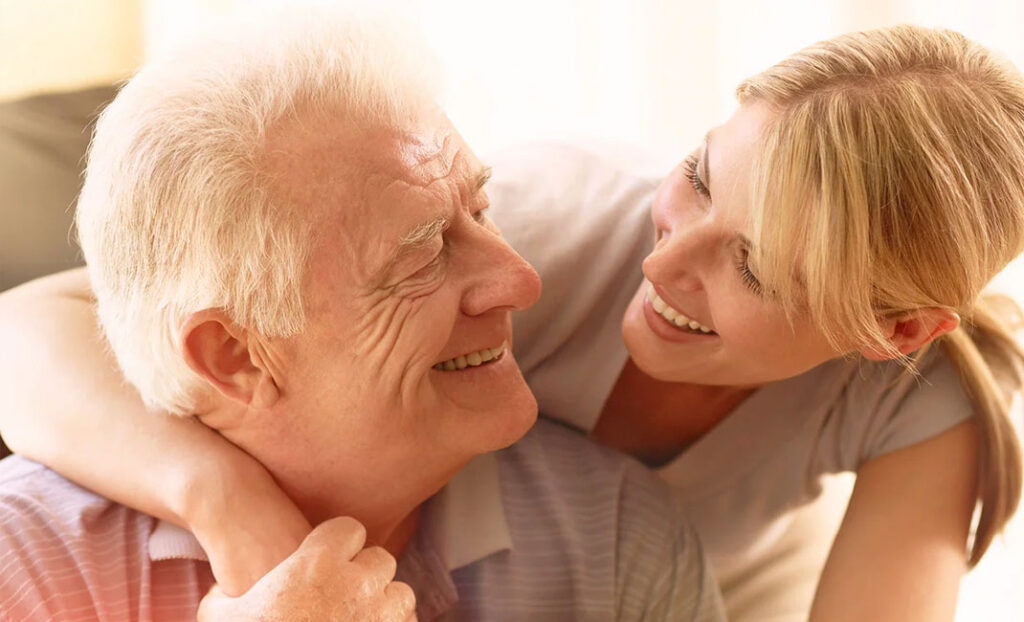 Ein älterer Mann wird von seiner Tochter freudestrahlend umarmt