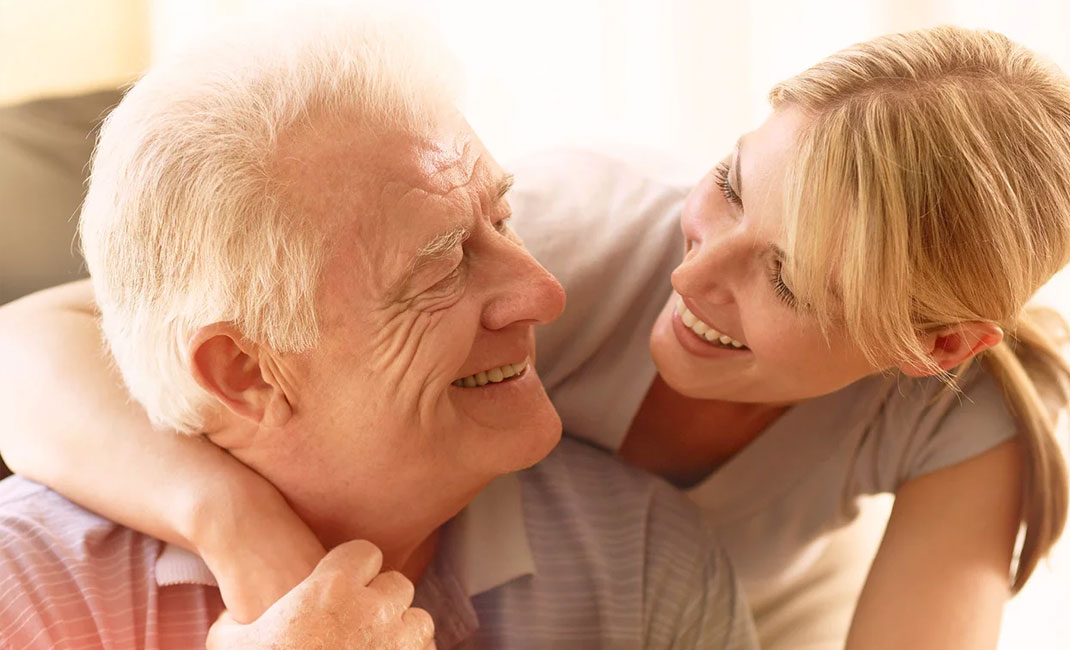 Ein älterer Mann wird von seiner Tochter freudestrahlend umarmt