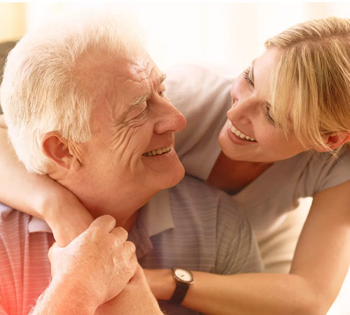 Ein älterer Mann wird von seiner Tochter freudestrahlend umarmt